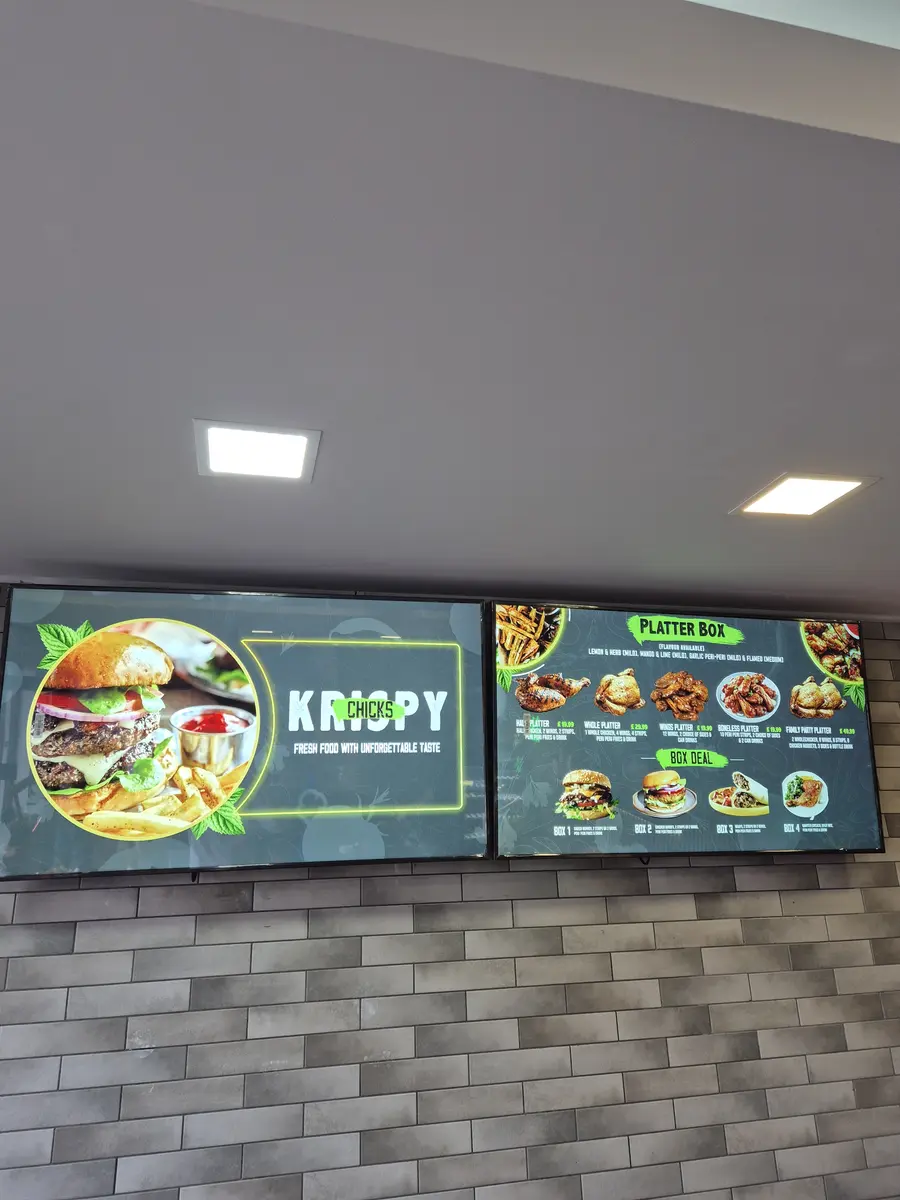 Portrait digital screen in a restaurant featuring food photography and prices.