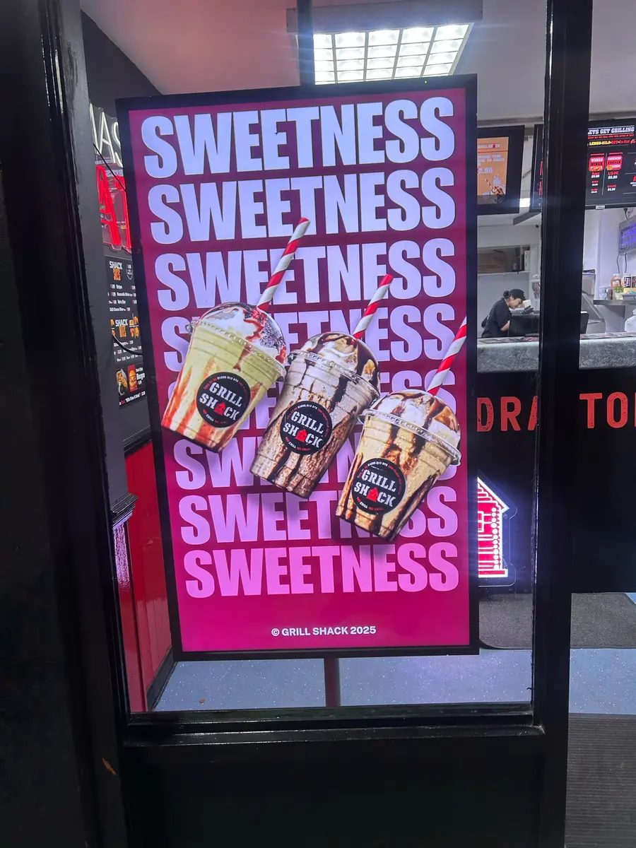 Digital menu board above a takeaway counter with bold food photography.