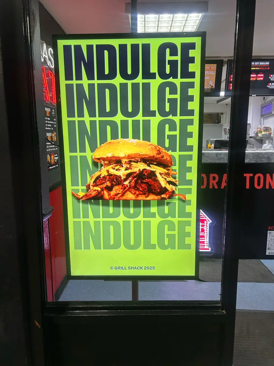Window-facing digital display attracting customers into a fast food shop.