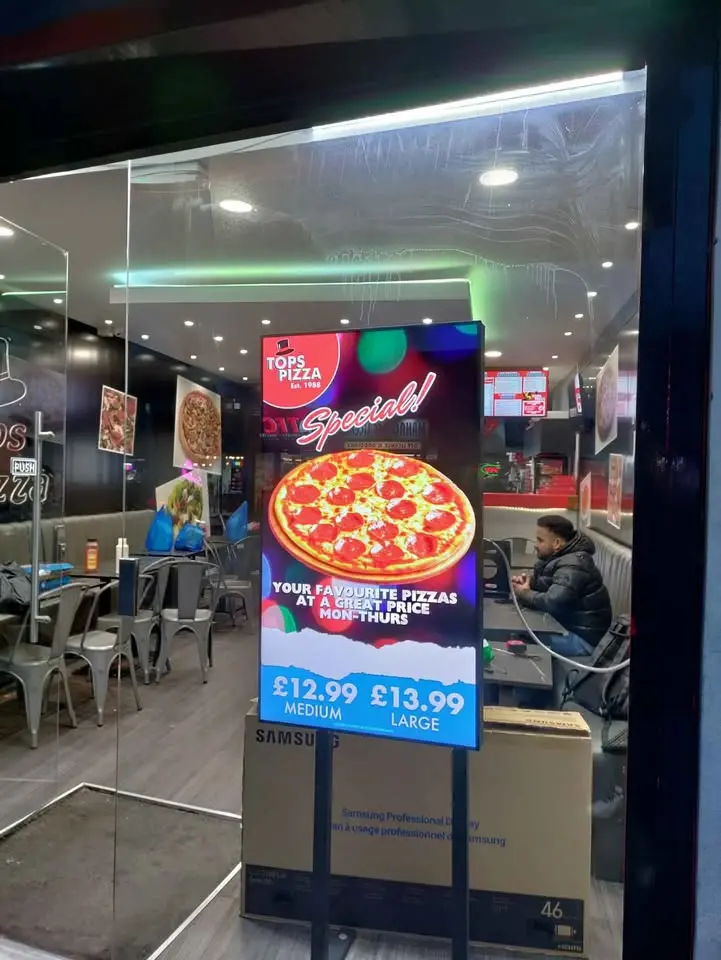 Bold digital menu board promoting meal deals in a UK takeaway.